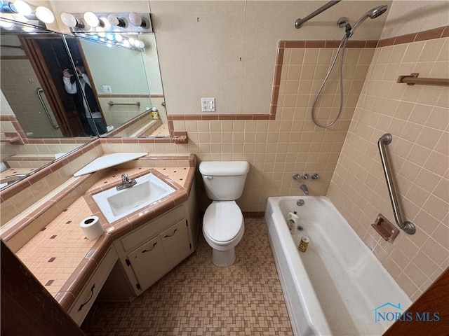 full bathroom with tiled shower / bath, vanity, tile walls, and toilet