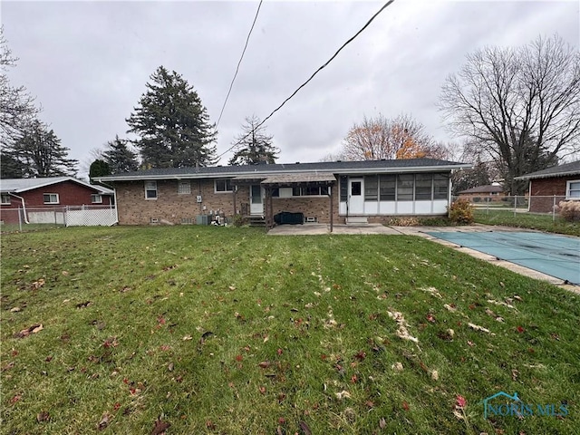 back of property featuring a sunroom, a yard, a patio, and a covered pool