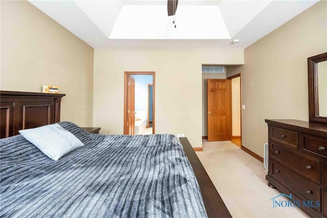 carpeted bedroom featuring a raised ceiling, a skylight, ensuite bath, and ceiling fan