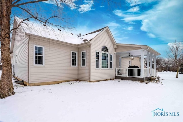 snow covered back of property with covered porch