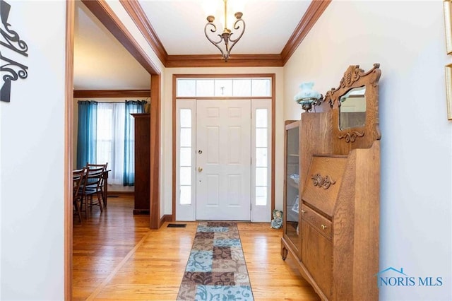 entryway with a chandelier, light hardwood / wood-style floors, and ornamental molding