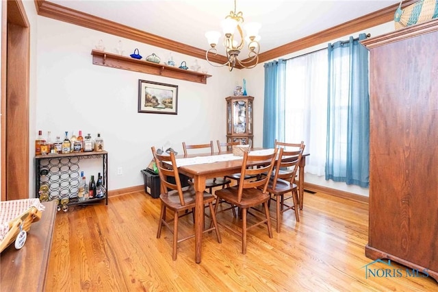 dining space with light hardwood / wood-style floors, an inviting chandelier, and ornamental molding