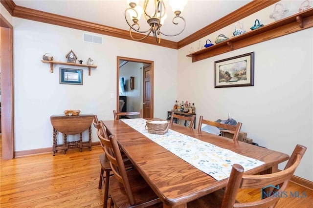 dining room featuring crown molding, light hardwood / wood-style flooring, and a chandelier