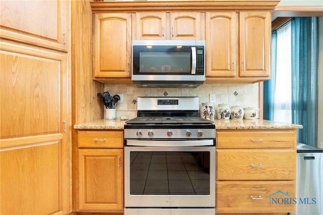 kitchen featuring light stone countertops, light brown cabinetry, backsplash, and stainless steel appliances