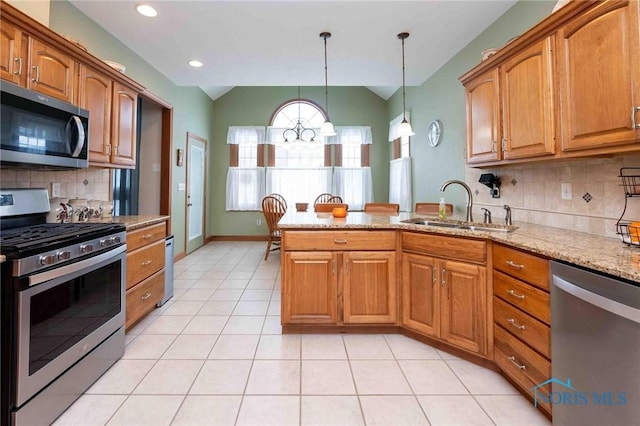 kitchen with sink, decorative backsplash, light stone countertops, appliances with stainless steel finishes, and decorative light fixtures