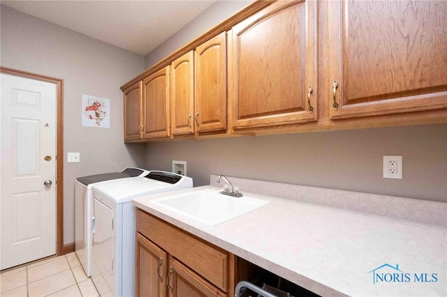 laundry area with cabinets, light tile patterned floors, washer and dryer, and sink