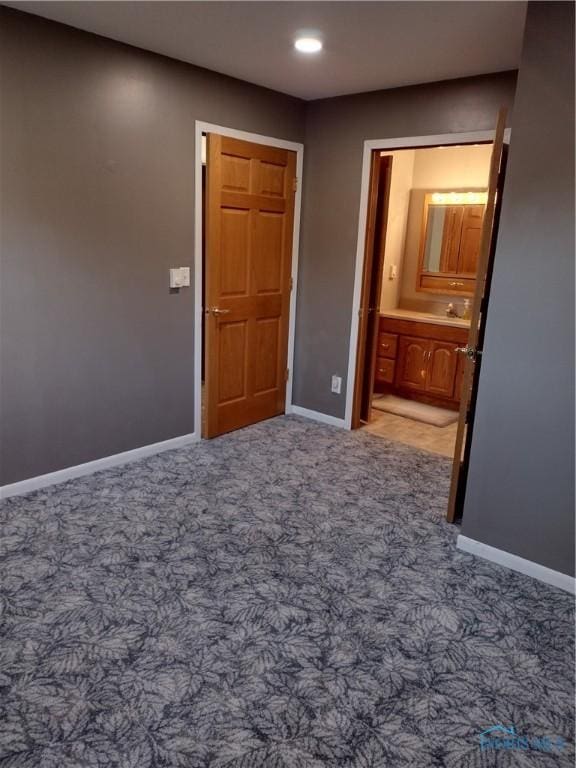 unfurnished bedroom featuring carpet floors, sink, and ensuite bath