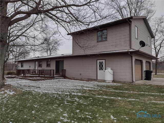 snow covered house featuring a lawn, a wooden deck, and a garage