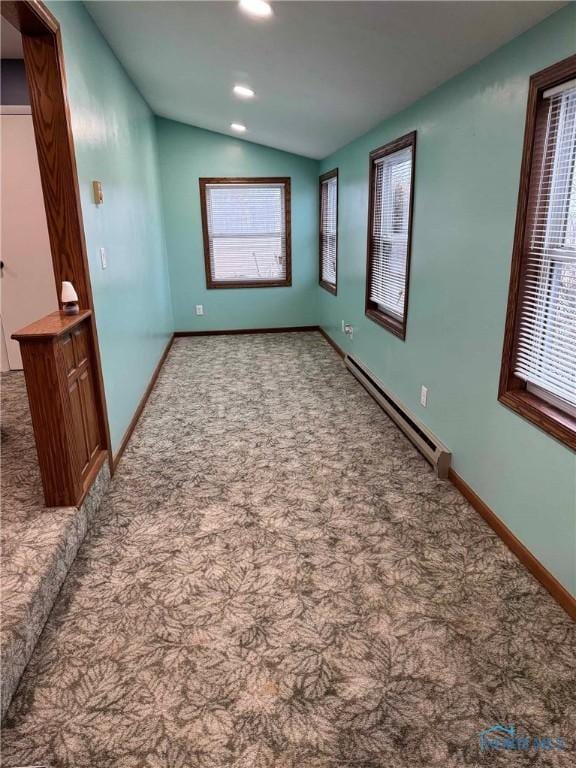 spare room with carpet flooring, vaulted ceiling, and a baseboard heating unit