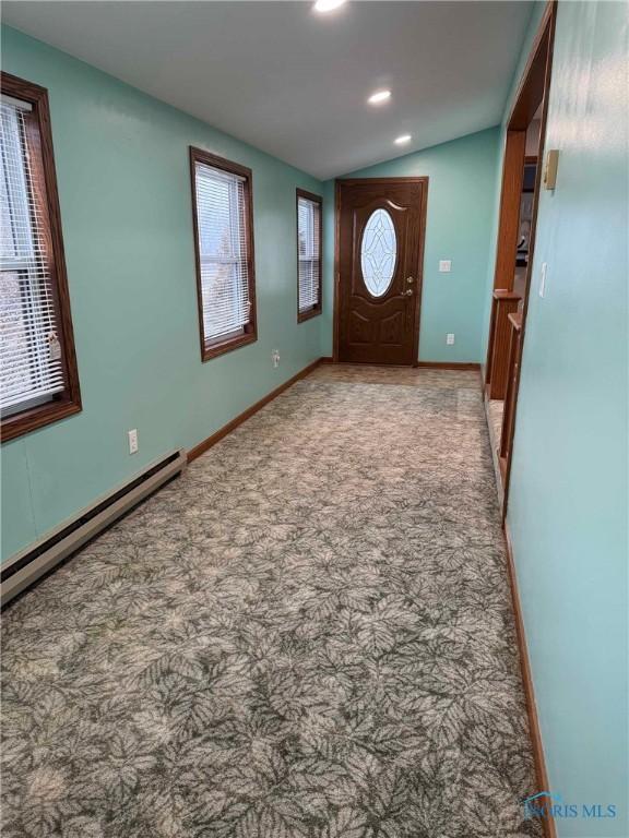 carpeted foyer featuring a baseboard radiator and lofted ceiling