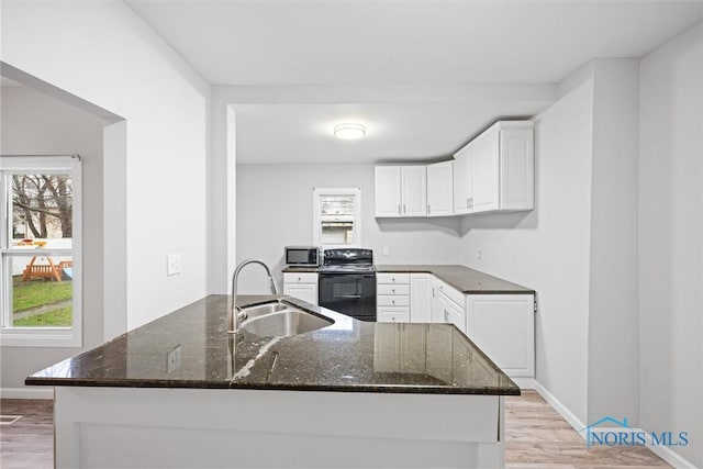 kitchen with white cabinetry, sink, black / electric stove, dark stone countertops, and light hardwood / wood-style floors