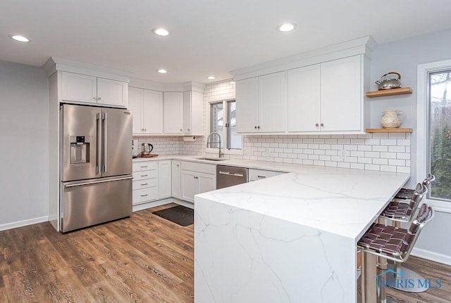 kitchen featuring sink, dark wood-type flooring, white cabinetry, stainless steel appliances, and light stone countertops