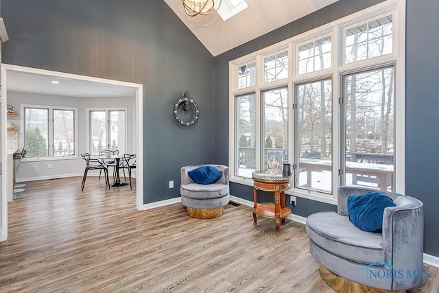 sitting room with high vaulted ceiling, a skylight, and hardwood / wood-style floors