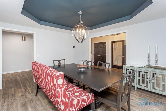 dining room featuring dark hardwood / wood-style flooring, a tray ceiling, and a chandelier