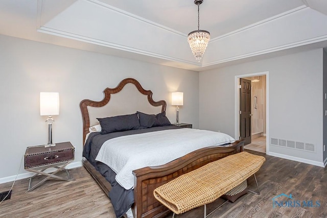 bedroom with crown molding, hardwood / wood-style floors, a tray ceiling, and a chandelier