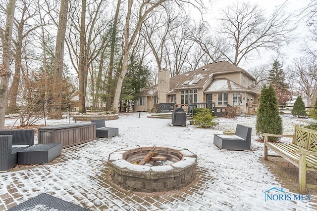 snow covered patio with a deck and an outdoor fire pit