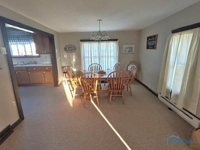 carpeted dining room with a baseboard heating unit, a notable chandelier, and sink