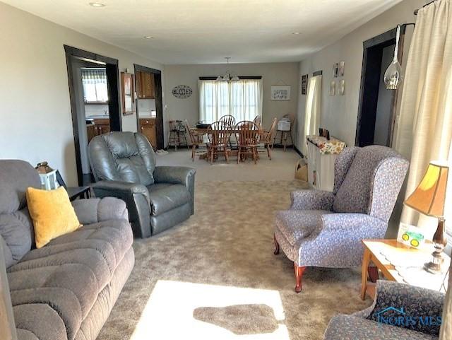 living room featuring carpet flooring and an inviting chandelier