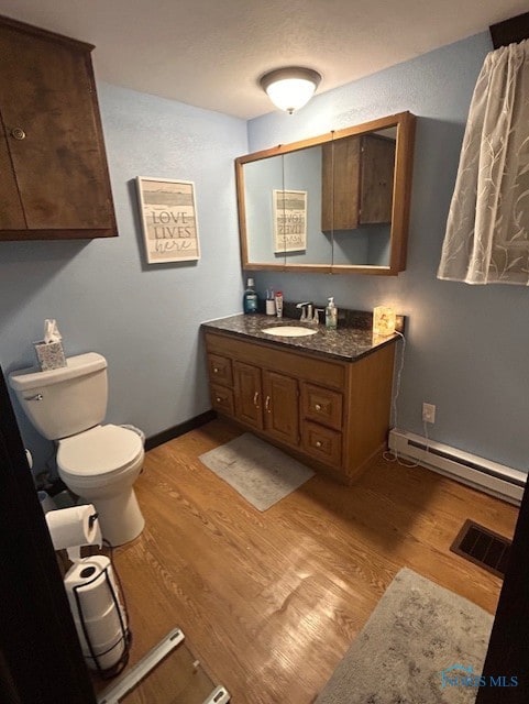 bathroom with hardwood / wood-style floors, vanity, a baseboard radiator, and toilet