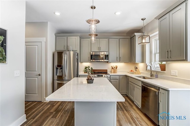 kitchen featuring gray cabinetry, sink, hanging light fixtures, appliances with stainless steel finishes, and a kitchen island