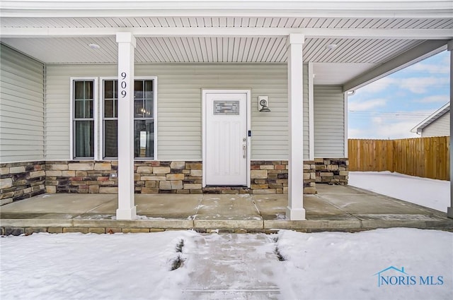 snow covered property entrance with a porch