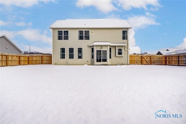 view of snow covered back of property