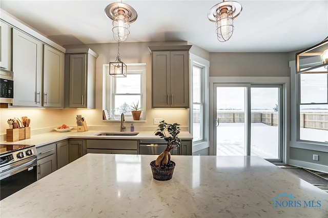 kitchen with appliances with stainless steel finishes, gray cabinets, light stone counters, and sink