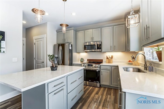 kitchen with appliances with stainless steel finishes, decorative light fixtures, a kitchen island, and sink