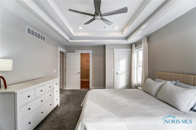 carpeted bedroom featuring a tray ceiling and ceiling fan