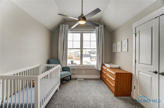 bedroom with carpet flooring, ceiling fan, a crib, and lofted ceiling