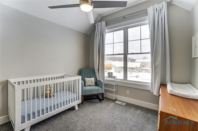 bedroom featuring ceiling fan, vaulted ceiling, dark carpet, and a nursery area