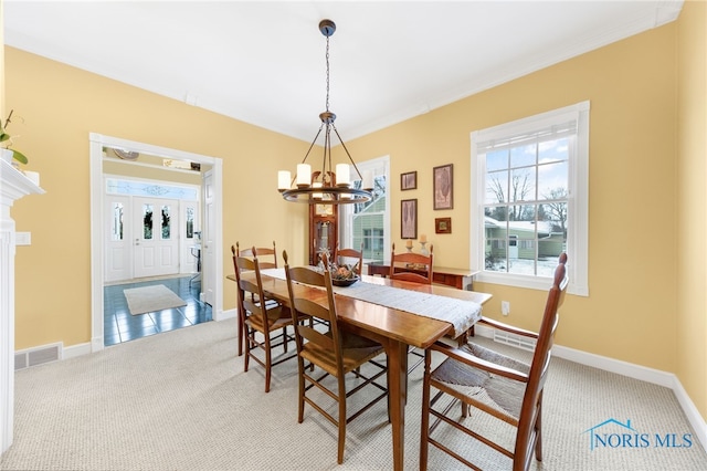 carpeted dining room with a chandelier