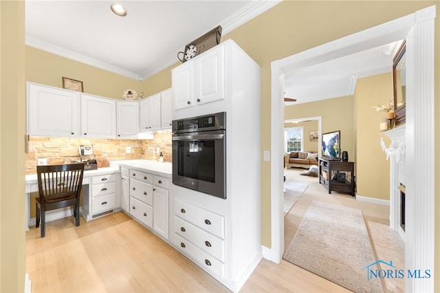 kitchen with backsplash, crown molding, oven, light hardwood / wood-style floors, and white cabinets