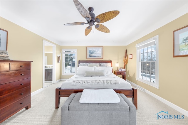 carpeted bedroom with ensuite bath and ceiling fan