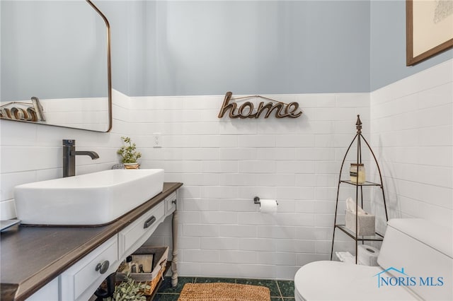 bathroom with tile patterned flooring, vanity, toilet, and tile walls