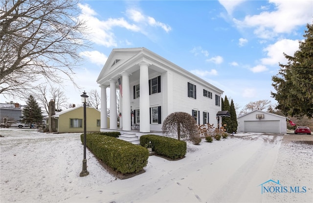 greek revival house featuring a garage and an outbuilding