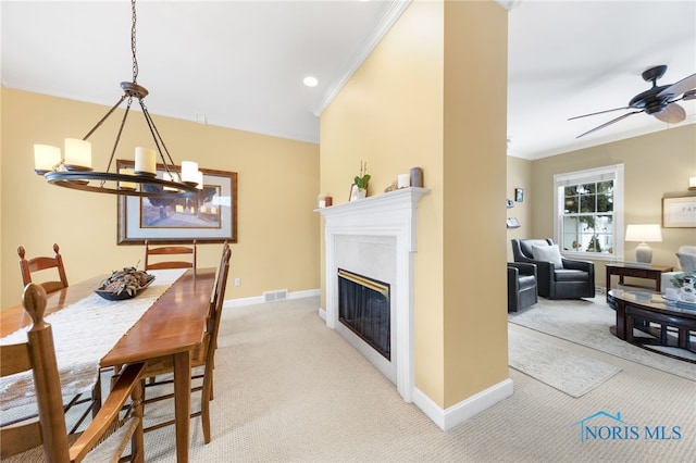 dining area with ceiling fan with notable chandelier, light colored carpet, and ornamental molding