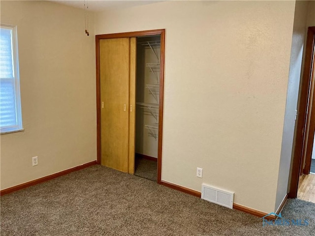 unfurnished bedroom with light carpet and a closet