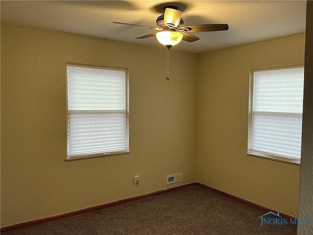 carpeted spare room with ceiling fan and plenty of natural light