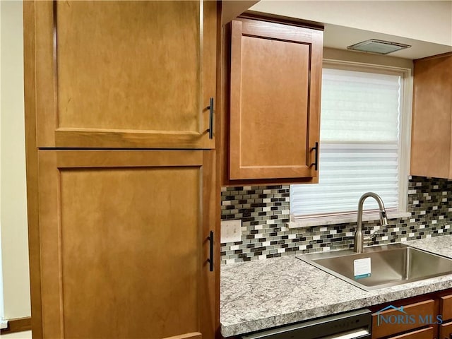 kitchen with tasteful backsplash, stainless steel dishwasher, and sink