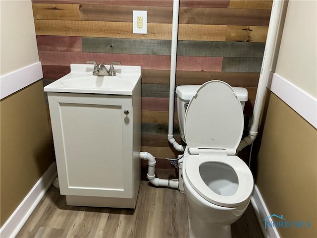 bathroom with wood walls, vanity, wood-type flooring, and toilet