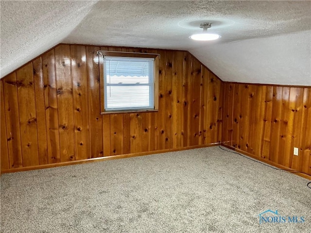 additional living space featuring a textured ceiling, carpet floors, and vaulted ceiling