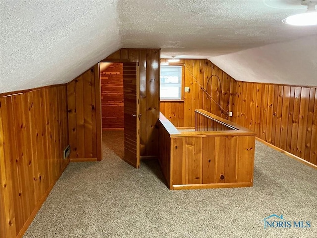 bonus room with vaulted ceiling, light colored carpet, and a textured ceiling