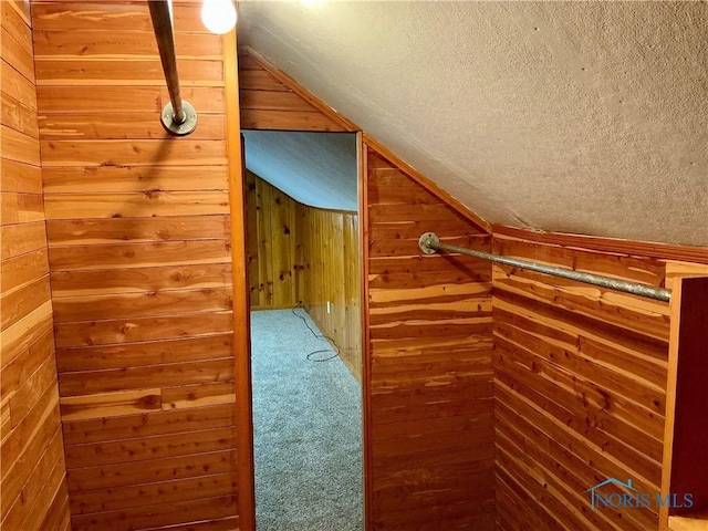 bonus room with carpet flooring, a textured ceiling, vaulted ceiling, and wooden walls