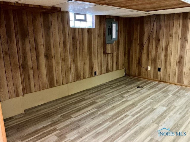 basement with electric panel, wooden walls, and hardwood / wood-style floors