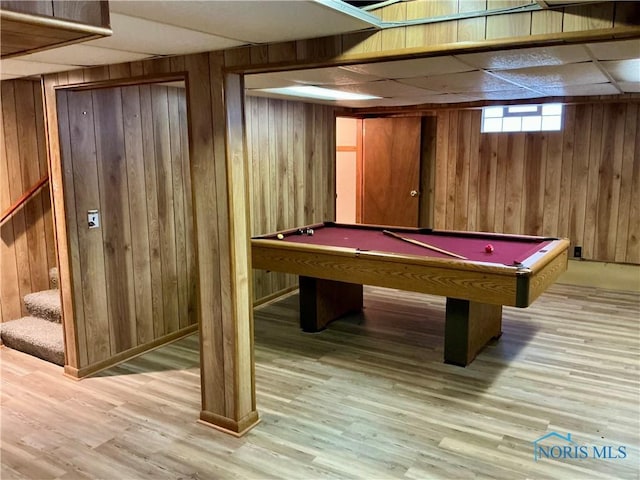 rec room with light wood-type flooring, a drop ceiling, wooden walls, and billiards