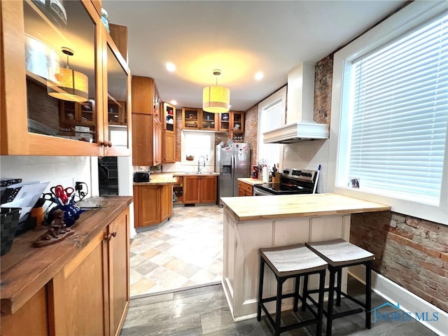 kitchen with a breakfast bar, decorative light fixtures, butcher block counters, custom exhaust hood, and stainless steel appliances