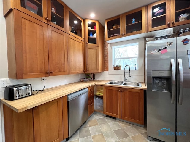 kitchen with stainless steel appliances, butcher block counters, sink, and decorative backsplash