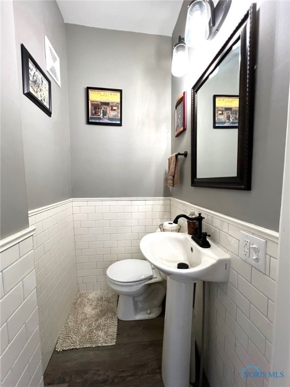 bathroom with tile walls, hardwood / wood-style floors, and toilet