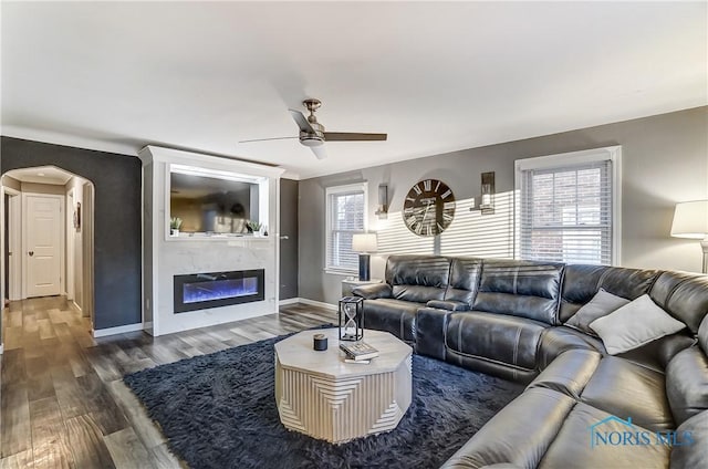 living room featuring dark hardwood / wood-style floors, ceiling fan, and a premium fireplace